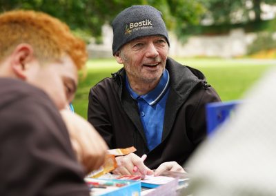 Two men at a picnic table. One is smiling.