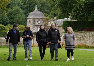 A group of people, talking and walking in a park.
