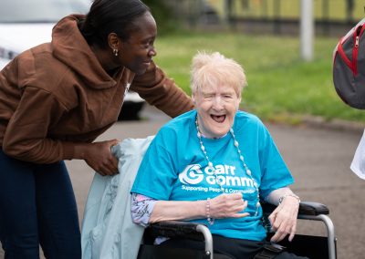 A younger woman leans over to chat to an elderly woman in a wheelchair.