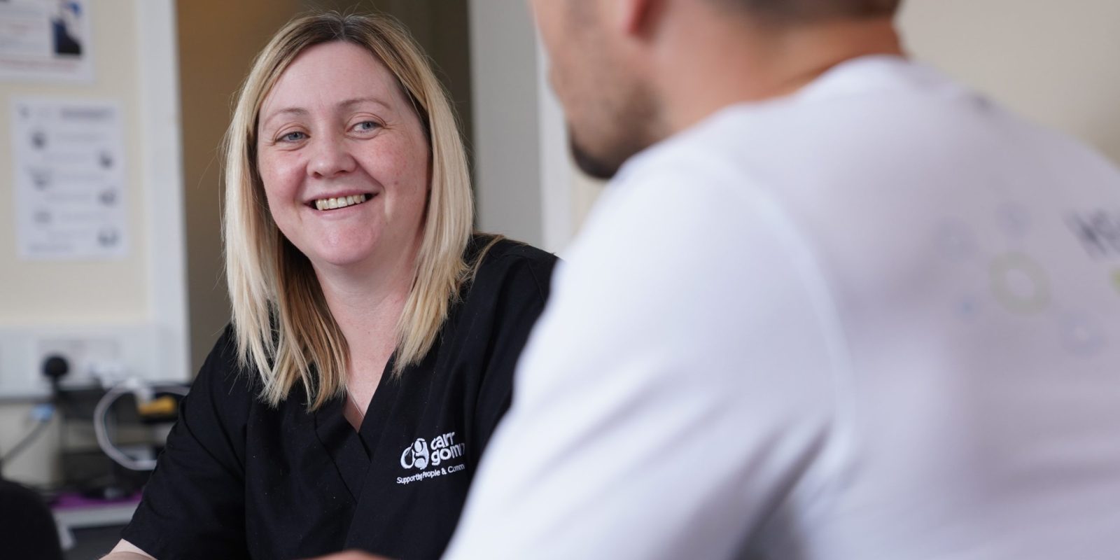 Blonde woman in dark top smiling at man who is off camera.