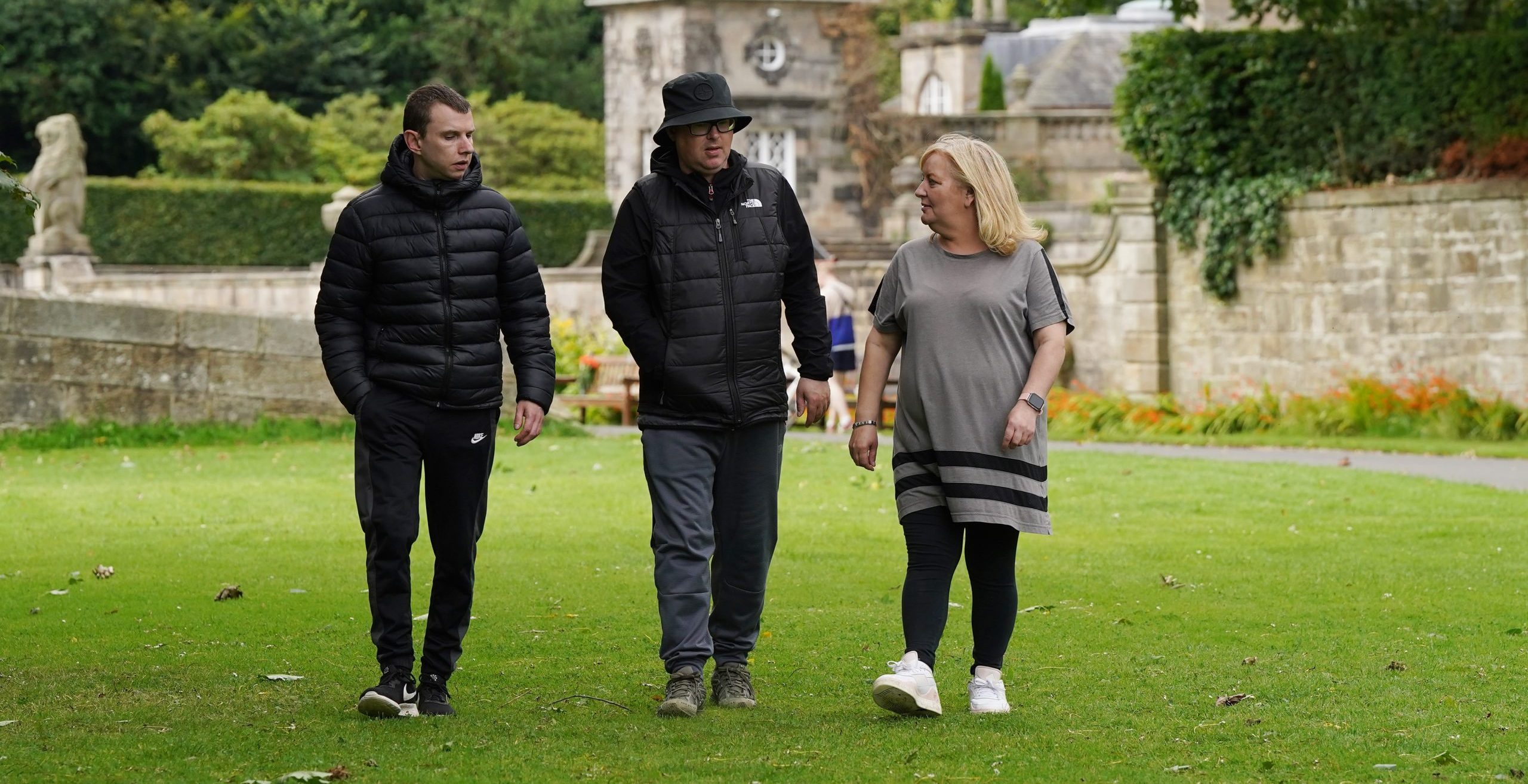 Two men and a woman talk while walking in a park environment. | Carr Gomm Mental Health Support