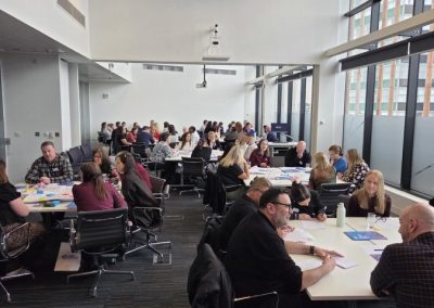 People sat around tables in groups of approximately 8, discussing together.