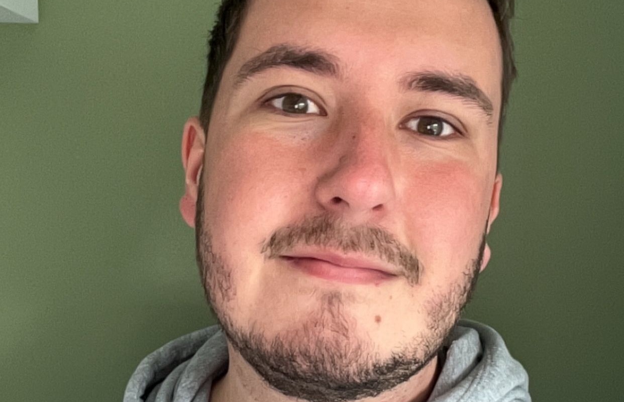 Man with brown hair and beard smiling at a camera