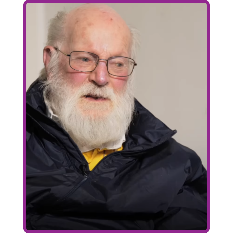 A photo portrait of a man in a black jacket with a white beard.