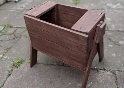 A handmade wooden raised planter, stained dark brown