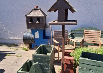 A collection of handmade wooden garden items including a bird house and raised planters