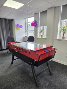 A room with a foosball table. Balloons are decorating the walls.
