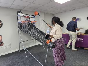 A white room with a woman playing a basketball game. A man is seen in the background.