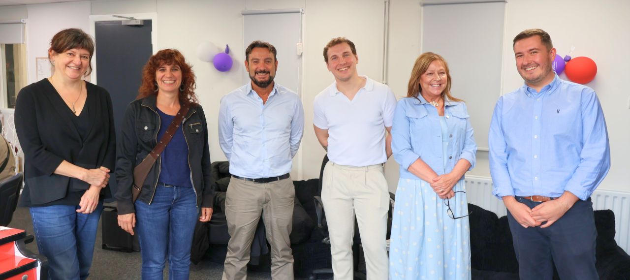 Five people are standing smiling to the camera.