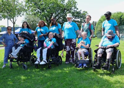 A group of people wearing blue Carr Gomm t-shirts on a grassy pitch.