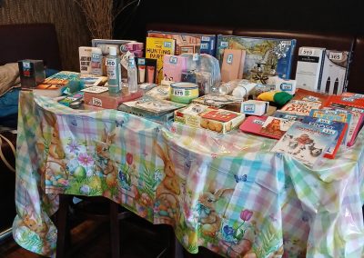 A table decorated with a colourful tablecloth displays a variety of raffle prizes