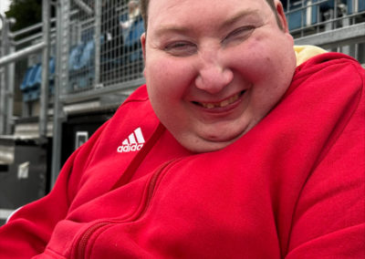 A man in a red hoodie smiles at the camera